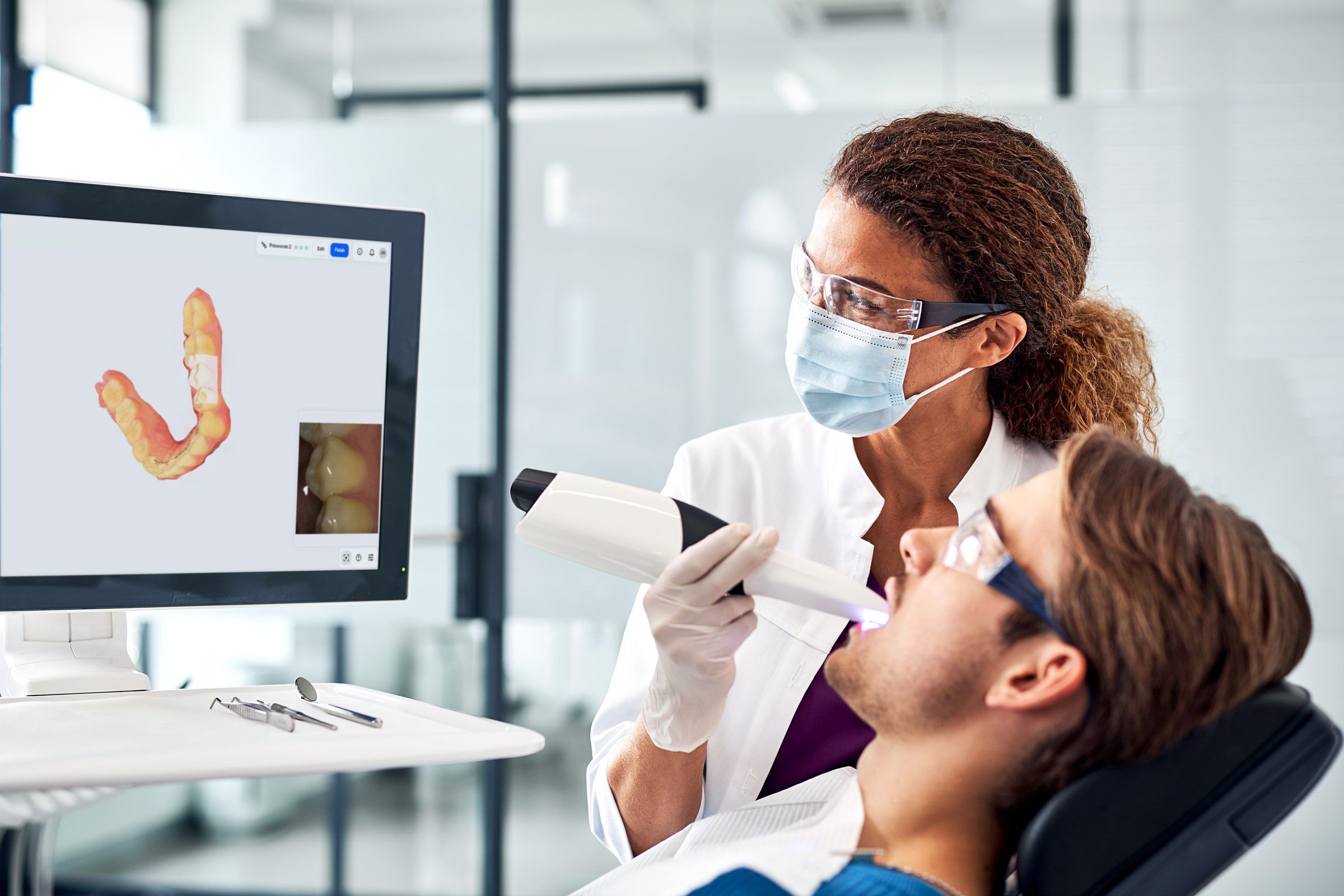Dentist taking a digital intraoral scan, with the 3D model on screen